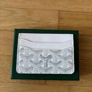 Vit Goy4rd plånbok - Säljer en stilren vit plånbok med deras ikoniska mönster. Plånboken har flera kortfack och är tillverkad i exklusivt skinn. Perfekt för dig som vill ha något både snyggt och praktiskt i fickan. Tveka inte för att ställa frågor.