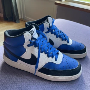 Nike skor blåa - Säljer ett par Nike Court Vision Mid sneakers i blått, vitt och svart i storlek 43 i man. Säljer skorna nästan oanvända då dem blev urväxta välldigt snabbt. (Säljer åt min brorsa). Skriv gärna vid funderingar.