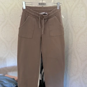 Beige mjukisbyxor från 157, stl S - Beiga mjukisbyxor från 157 med bred resår och snörning i midjan. Byxorna har två stora fickor framtill och är gjorda i mjukt bomullsmaterial. Perfekta för chill dagar eller när du vill vara extra bekväm.