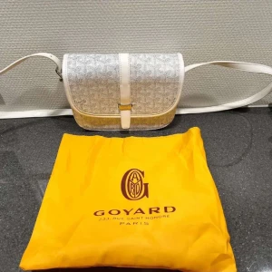 Vit axelväska från Goya3d - Säljer en snygg vit axelväska från Goya3d med klassiskt mönster och justerbar rem. Väskan har lock med spänne och är tillverkad i exklusivt skinn. Perfekt för dig som vill ha något unikt och stilrent.