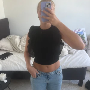 Svart kort topp med volanger  - Säljer denna söta korta toppen med detaljer på armarna❤️ Tröjan är i toppskick och har inga tecken på användning❤️