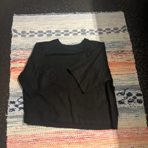 Svart stickad tröja från 157 - Svart stickad tröja från 157 i storlek M. Tröjan har en enkel och clean design med rund hals och trekvartsärm. Perfekt för dig som gillar minimalistisk stil och vill ha något som funkar till många olika outfits.