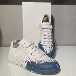 Maison Margiela sneakers med blå färgstänk - Unika sneakers från Maison Margiela har haft dem 1 gång✅ och är i jätte fint skicka tveka inte att ställa frågor om du har nån fundering🍾🥂