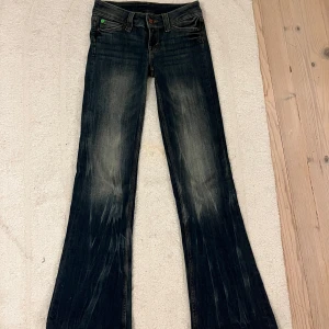 Cheap monday Bootcut jeans Bootybei med grön patch - Jättesnygga lågmidjade mörkblå bootcut jeans från cheap monday i modellen booty bei med snygg wash och cool grön patch bak i midjan. Klassisk femficksmodell med låg midja och utsvängda ben. Jeansen är i bomull med en hint av stretch för skön passform. Endast använda två gånger och säljer dem då de är lite för små för mig. Hör av dig om du vill ha fler bilder!💕