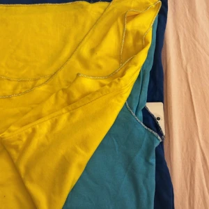 Färgglad ärmlös linne  - Snygg ärmlös linne  i bomull med rund halsringning och kontrastsömmar. Finns i tre färger: knallgul, turkos och marinblå. Perfekt för dig som gillar färg och enkel stil. Lätt och skön att bära under varma dagar.