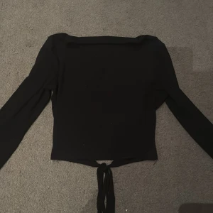 Svart långärmad topp med knyt - Säljer en svart långärmad topp med snygg knytning i midjan. Aldrig använd. Skriv för bilder å info! (öppet pris) Skriv innan du köper