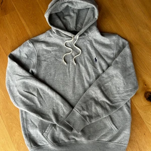 Grå hoodie från Ralph Lauren - Halloj! Säljer denna grå hoodie från Polo Ralph Lauren med deras klassiska logga på bröstet. Tröjan sitter riktigt gött och croppar till vid sömmen längst ner. Perfekt för chill dagar eller att ha i skolan. Vid frågor är det bara att höra av sig till mig, allt gott!