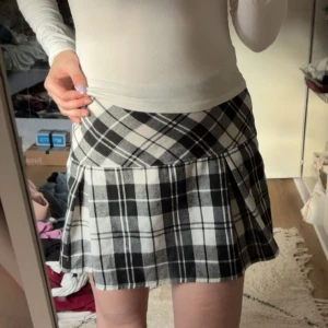 Rutig svartvit kjol från Shein - Supersnygg kort kjol från Shein i svartvitt rutigt mönster. Kjolen har en lätt utställd form och är sydd i ett mjukt tyg som känns skönt mot huden. Perfekt för dig som gillar en trendig och ungdomlig stil.