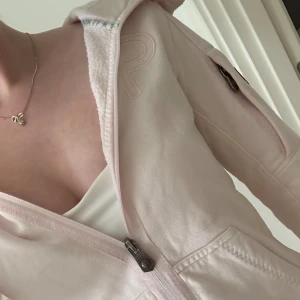 Ljusrosa hoodie från Pelle P - Ljusrosa hoodie från Pelle P med dragkedja, huva och broderad logga på bröstet. Mjuk insida i fleece, fickor fram och en extra ficka med dragkedja på ärmen. Tillverkad i 80% bomull och 20% polyester. Perfekt för chill dagar. Nypris: 900kr, Världens finaste färg!!!