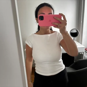 Vit ribbad topp från Gina tricot - Säljer en fräsch vit topp med ribbad struktur och korta ärmar. Modellen är slim och har en snygg, lite bredare halsringning. Perfekt att styla med jeans eller kjol för en clean look. Materialet är mjukt och stretchigt, vilket gör den skön att bära hela dagen.