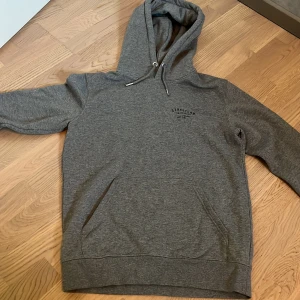 Grå hoodie från Streetlab Skateboard - Säljer en grå hoodie från Streetlab Skateboard med svart tryck både fram och bak. Tröjan har huva med snörning, stor magficka och långa ärmar. Den är inte mycket använd i storlek S men den är ganska stor. 