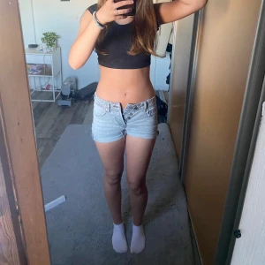 Ljusgrå jeansshorts med låg midja - Säljer ett par ljusgrå jeansshorts med låg midja och knappar iställer för kedja