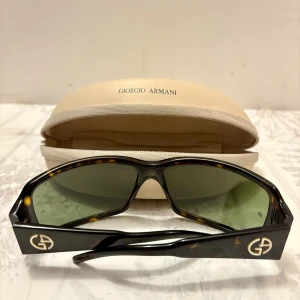 Solglasögon Giorgio Armani - Väldigt fina solglasögon från Giorgio Armani som jag fick som gåva men har aldrig använts ute. Svart färg med inslag av mönster. Passar både Män och Kvinnor (Unisex). Fodral och duk för att rengöra glasögonen ingår.   Modell: GA 196/S  Finns att hämta i Rågsved eller mötas upp söder om stan.  Hör gärna av dig vid frågor eller funderingar!