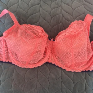 Korallrosa spets-bh från Freya - Säljer en snygg korallrosa bh från Freya med vacker spets och justerbara axelband. Bh:n har dekorativa spetsdetaljer och hakknäppning bak. Materialet är mjukt och stretchigt med 84% polyamid och 16% elastan. Perfekt för dig som gillar färg och fina detaljer!
