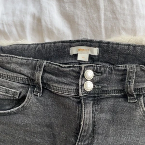 Gråa Flare låg midjade jeans från GinaTricot - Snygga gråa låg midjade jeans från Gina Tricot i stl 164. Byxorna har dubbla knappar fram, klassiska fickor och bakfickor med lock och knapp. Perfekt kondition och säljer då dem har inte kommit till användning🩷🩷