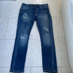  Jack & Jones jeans - Snygga blå jeans från Jack & Jones med slitna detaljer och lätt tvättad look. Modellen är Slim Glenn!