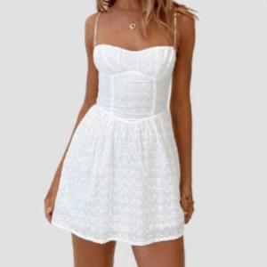 Vit sommarklänning med spetsdetaljer - Charmig vit klänning med smala axelband och spetsdetaljer. Den har en figurnära överdel och en luftig kjol som ger en romantisk känsla. Perfekt för varma sommardagar och studenten!  Klänningen är helt oanvänd!  (Lånad bild från hemsidan som klänningen är beställd ifrån) #studentklänning #vit #kortklänning #utspringsklänning