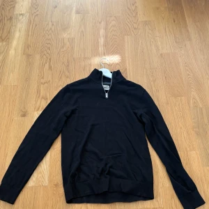 Svart half zip tröja Jack & Jones XS - Svart långärmad tröja från Jack & Jones i storlek XS. Tröjan har en stilren half zip-dragkedja vid halsen och ribbade muddar vid ärmslut och nederkant. Materialet är mjuk bomull som känns skönt mot huden. Perfekt för dig som gillar enkel och clean stil. Köpt för 500kr mitt pris 199kr.