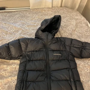 Svart dunjacka Peak Performance 170 - Hej! Säljer nu min svarta dunjacka från Peak Performance i storlek 170 då den är på gränsen att bli för liten. Använd väldigt mycket men är fortfarande bra skick. Jackan har huva, dragkedja framtill och logga på  bröstet och på ärmen. Perfekt för kalla dagar. Bara att fråga om närmare bilder, pris kan diskuteras.🩷