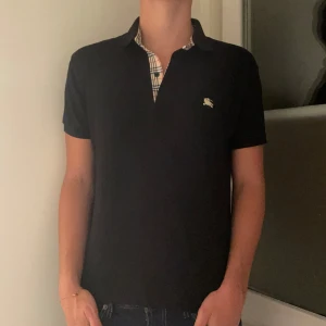 Burberry Piké - Säljer denna riktigt feta pikén ifrån Burberry i en clean svart färg tillsammans med deras ikoniska mönster på kragen. Storlek M men sitter tight så skulle nog mer passa någon med storlek S. Bra skick utan några defekter och enbart använd ett fåtal tillfällen. Nypris ligger på 4000, mitt pris enbart 399. Hör gärna av dig innan köp eller vid andra frågor!☺️