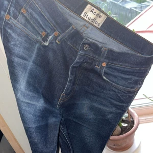 Raw denim jeans från Acne Studios - Säljer ett par ofantligt snyggt fadeade mörkblå jeans från Acne Studios med klassisk femficksdesign. Jeansen har en rak och slim passform med subtila och högt eftertraktade slitningar. Perfekta till vardags och lätta att matcha med olika stilar. Storlek W30 L32.