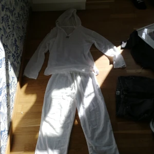 Vita linnebyxor - Säljer ett par luftiga vita linnebyxor med resår i midjan. Perfekta för varma dagar och ger en avslappnad stil. Byxorna har raka ben och är tillverkade i ett svalt material.