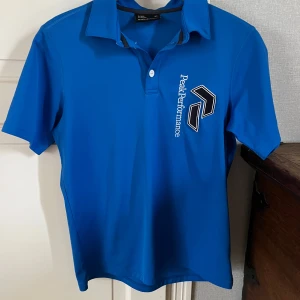 Blå piké t-shirt från Peak Performance - Säljer en blå piké t-shirt från Peak Performance. Bra skick och perfekt som golftröja😁