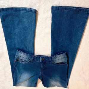 Blå bootcut jeans - Säljer ett par klassiska blå bootcut jeans med normal passform. Jeansen har fem fickor, bälteshällor och knappgylf. Perfekta för dig som gillar en lite vidare siluett nertill. Snygg tvätt och sköna att bära.