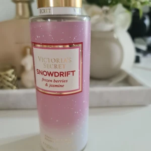 Victoria's Secret Snowdrift Body Mist - En body mist från Victoria's Secret med doften Snowdrift. Doften har inslag av frysta bär, jasmin och en hint av tangerin. Flaskan är rosa med vita prickar och har ett guldfärgat lock. Perfekt för dig som gillar fruktiga och blommiga dofter. Tagit max 3 sprut, i princip som ny. Victorias secret