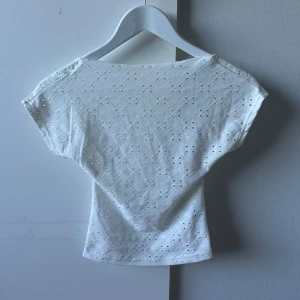 Rygglös topp med broderade blommor - Säljer en vit rygglös topp med broderade blommor över hela tröjan🩷
