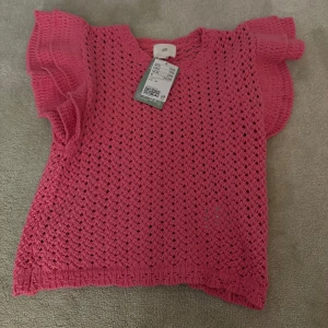 Rosa stickad topp från H&M - Säljer en söt rosa stickad topp från H&M med korta volangärmar.