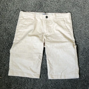 Beige linneshorts - Snygga beige shorts i linne med normal passform. Klassisk design med knapp och dragkedja framtill samt sidofickor. Perfekta för varma dagar och enkel att matcha med olika toppar.