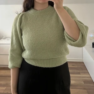 Ljusgrön stickad tröja - Mysig ljusgrön stickad tröja med rund hals och ribbade muddar. Tröjan har en något croppad passform och långa ärmar med lätt puff vid axlarna. 