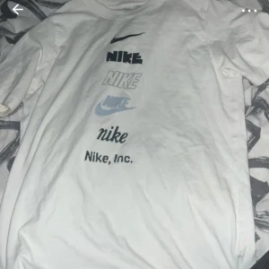 Vit t-shirt med olika Nike-loggor - Säljer en vit t-shirt från Nike med flera olika tryck av Nike-loggan på framsidan. T-shirten har rund halsringning och är kortärmad. Perfekt för dig som gillar sportiga och stilrena plagg.