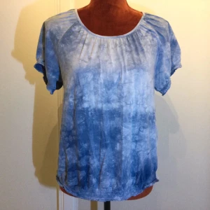 Blå Batik T shirt Kappahl Strl: S - Säljer en blå t-shirt med batikmönster och rund halsringning. T-shirten har korta ärmar och en avslappnad passform. Perfekt för en avslappnad stil. Storlek uppskattad! Bomull Resår i ärmslut och nertill. Katter finns i hemmet!