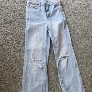 Ljusblå jeansbyxor från LAB Industries - Ljusblå jeansbyxor från LAB Industries med raka ben och slitna detaljer vid knäna. Klassisk femficksmodell och normal passform. Perfekta för en avslappnad stil.