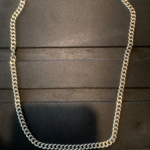 Silverfärgat halsband i kedjemodell - Stilrent halsband i silverfärg med kraftig kedjelänk. Märkt med 925 vilket indikerar äkta silver. Perfekt accessoar för att lyfta din stil. Klassisk design som passar till många tillfällen.