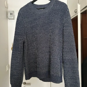 Blå stickad tröja - Säljer en blå stickad tröja med rund halsringning. Tröjan har lång ärm och ett grovt stickat mönster som ger en avslappnad och mysig känsla. Perfekt för kyligare dagar och enkel att matcha med jeans eller byxor. Märke Cos. Storlek M 