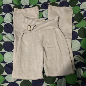 Blå stickade byxor med bälte  - Säljer ett par blå stickade byxor med bred ribbad midja och dekorativt bälte i midjan. Byxorna har en rak och loose passform, perfekta för en avslappnad stil. Mjukt och bekvämt material. Använda en gång❤️