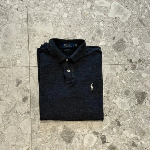 Mörkgrå pikétröja från Polo Ralph Lauren - Säljer en mörkgrå pikétröja från Polo Ralph Lauren med vit broderad logga på bröstet. Nypriset=1599