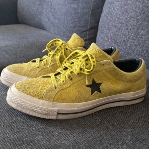 Gula Converse One Star sneakers - Säljer ett par gula Converse One Star sneakers (loyal to fin) i mocka med svart stjärndetalj på sidan. Skorna har gula snören med svart text och vit sula med svart rand. Perfekta för dig som vill sticka ut med färg på fötterna. Pris kan diskuteras 