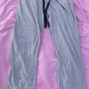 Grå mjukisbyxor från Isolde - Grå mjukisbyxor från Isolde med elastisk midja och svart dragsko. Byxorna är raka i modellen och tillverkade i mjukt bomullsmaterial, perfekta för en avslappnad stil.