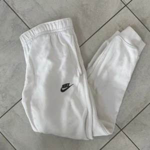 Vita mjukisbyxor från Nike - Säljer ett par vita mjukisbyxor från Nike med svart logga på vänster ben. Byxorna har resår i midjan och vid bensluten samt fickor på sidorna och bak. Perfekta för en avslappnad stil. Nypris runt 500kr, mitt pris 200kr. Men kom gärna med prisförslag!