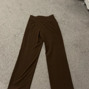 Bruna kostymbyxor från Pull&Bear - Säljer ett par bruna kostymbyxor från Pull&Bear i storlek S. Byxorna är midwaist och raka. Sparsamt använda