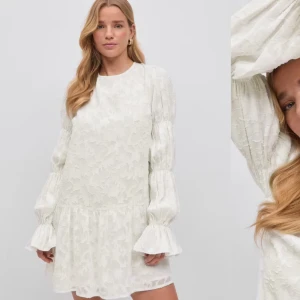 Slutsåld volang klänning - Superfin vit klänning med subtilt blommönster och volangdetaljer på ärmarna, som är helt ny med prislappen kvar! Perfekt till skolavslutning, student & konfirmation 💕