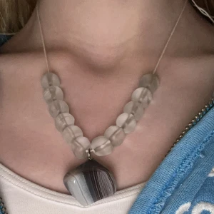 Halsband med stora pärlor och stenberlock - Unikt halsband med stora, matta pärlor i transparent grått och en hängande stenberlock med naturliga mönster i grå och vita toner. Perfekt statement-accessoar för dig som gillar personliga smycken. Justerbar!