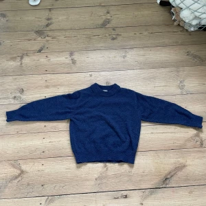 Mörkblå stickad tröja - Mysig mörkblå stickad tröja med rund halsringning och ribbade muddar vid ärmslut och nederkant. Tröjan har lång ärm och en klassisk, enkel design som passar till många olika stilar.