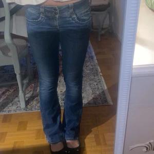 Blå bootcut jeans med låg midja - Säljer nu en av mina favorit jeans då jag har så många. Det är ett par blåa pepe jeans med låg midja. De är lagade från slitningar mellan benen, så där av syns det att jag lagat dom lite grann. Hör av er vid mer frågor💕Det passar mig som brukar ha storlek 34/36 i jeans. Jag är 164 och det passar mig perfekt i längden🙏🏼