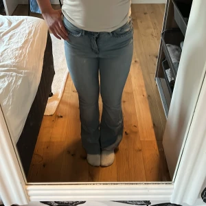 Ljusblå bootcut jeans med flätad detalj - Säljer ett par ljusblå jeans med bootcut passform och snygg flätad detalj vid fickorna. Jeansen har klassisk femficksdesign och normalhög midja. Perfekta för dig som gillar en retroinspirerad look.