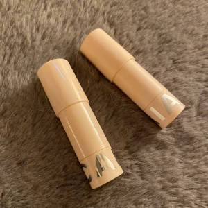 Beige stick highlighter från CAIA - Två stycken krämiga highlighter-sticks från Saie i beige hylsa med silvrig logga. Perfekta för att ge glow till kindben, näsrygg och amorbåge. Smidig stickform som är enkel att applicera direkt på huden.